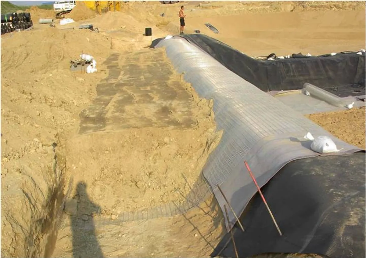 Liner geosintetik terpasang di cekungan kolam penampungan yang digali