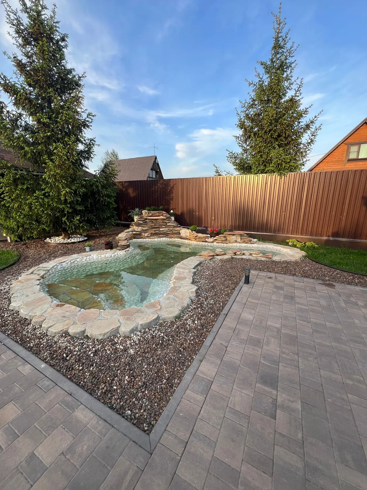 A finished garden pond with a stone-and-plant edge concealing the pond liner